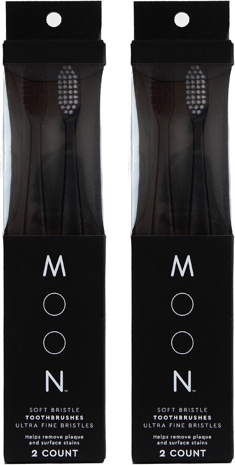 Four black manual toothbrushes with extra-soft tapered bristles in individual black packages.
