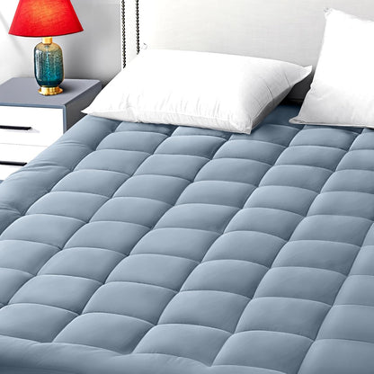Soft blue quilted mattress topper fitted securely over queen bed
