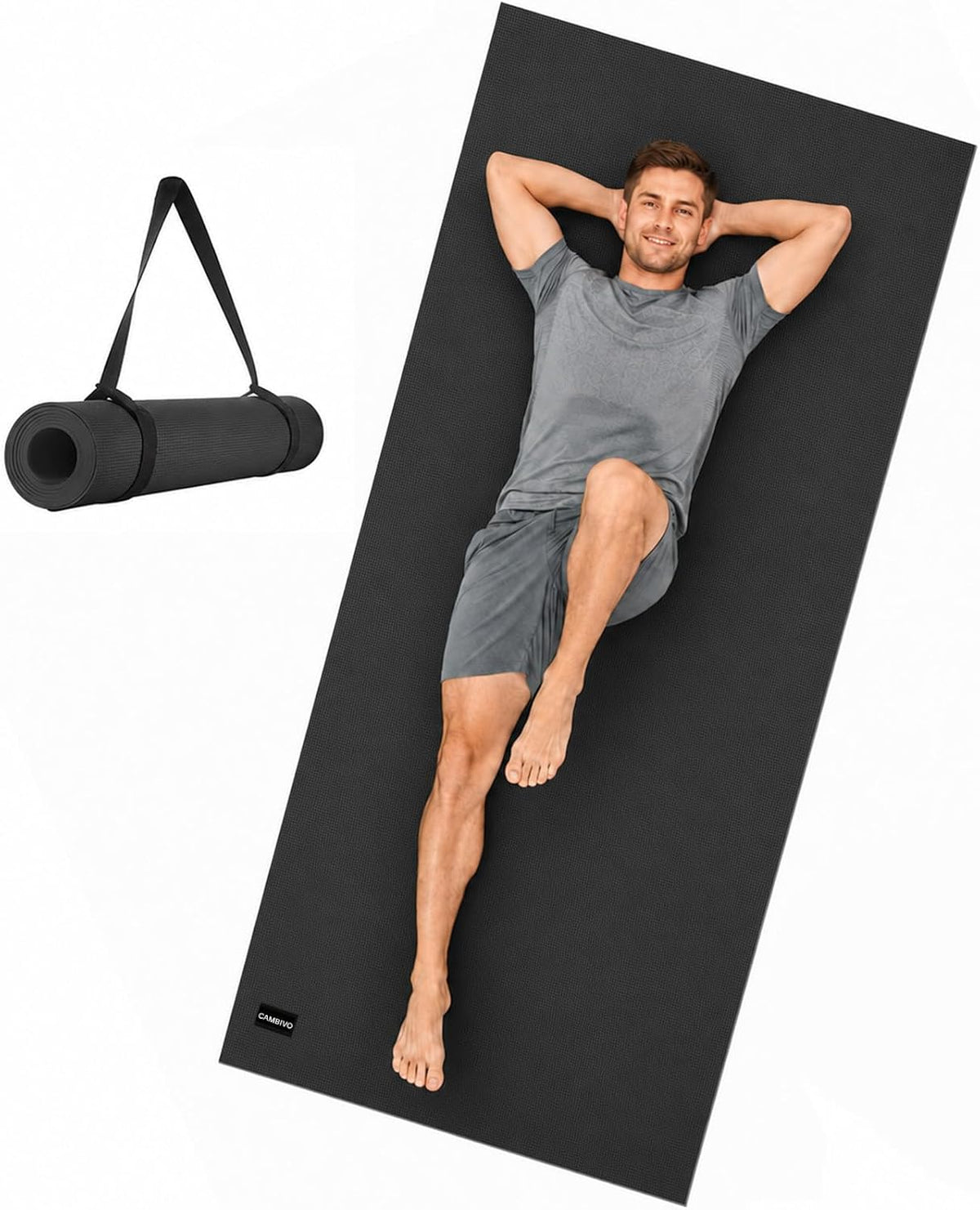 Black extra-long wide yoga mat with a man lying on it, alongside the mat rolled and secured with a carrying strap.