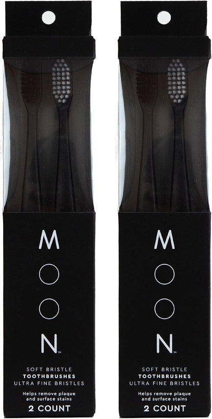 Four black manual toothbrushes with extra-soft tapered bristles in individual black packages.