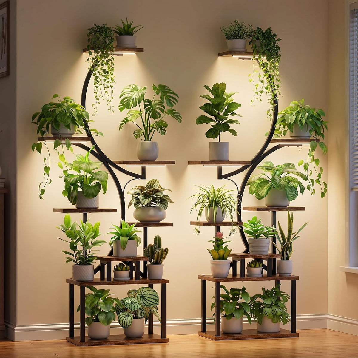 Two S-shaped indoor plant stands with integrated grow lights, wood-look shelves, and multiple potted green plants in a modern living room.